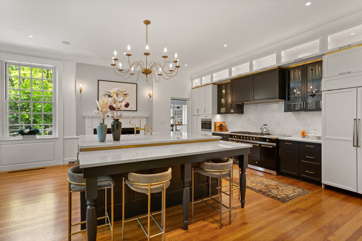 Large kitchen with black cabinets and a chandeleir over kitchen island
