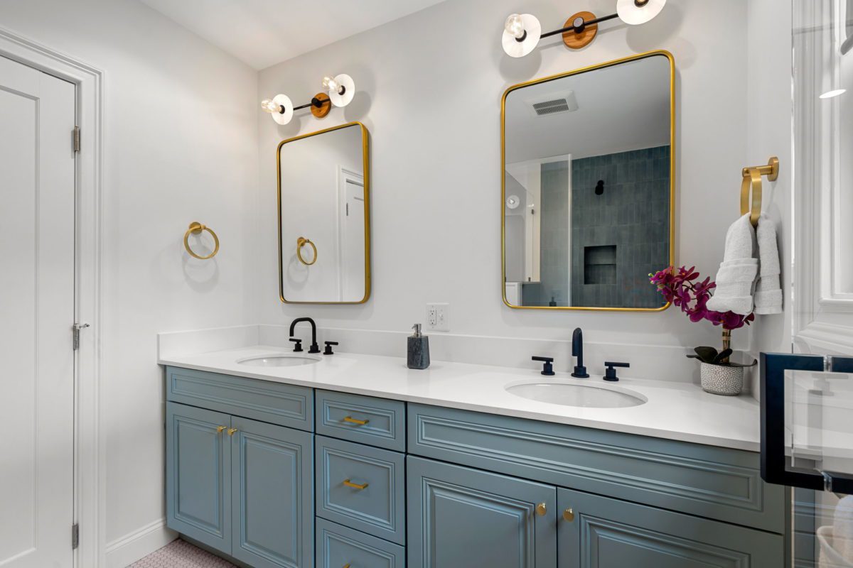 Real estate photo of double vanity with blue cabinets and black faucets